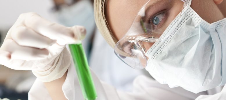 compounding pharmacist examining a test tube wearing cleanroom ppe and supply