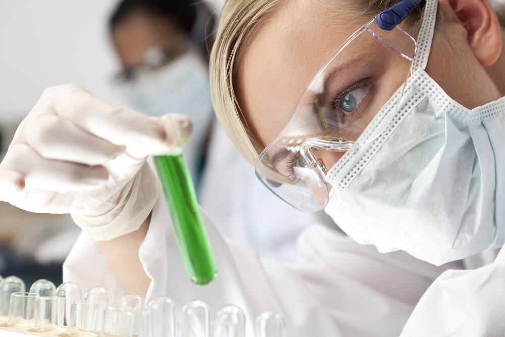 compounding pharmacist examining a test tube wearing cleanroom ppe and supply