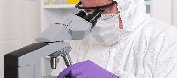 pharmacist using microscope wearing cleanroom ppe and supply
