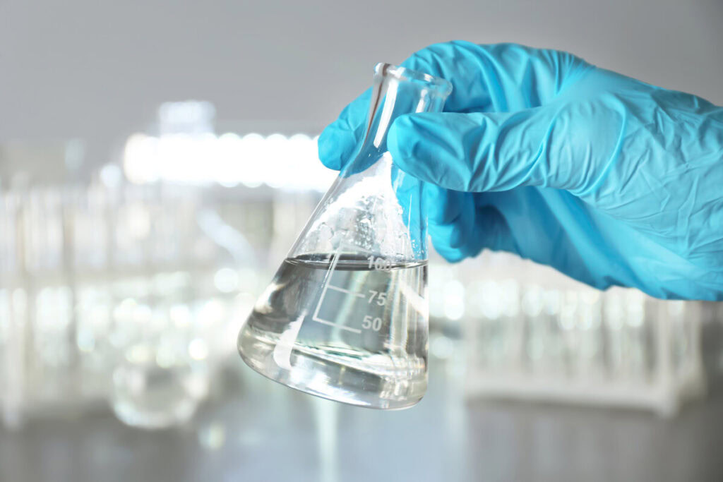 laboratory worker holding flask with water on blurred background