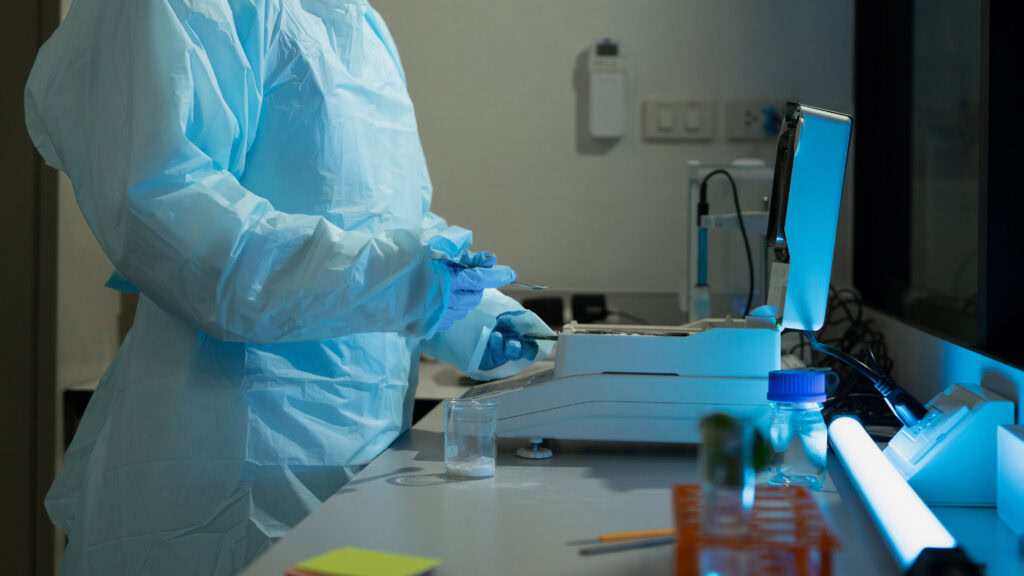 scientist in protective suit working with laboratory equipment and samples in research facility