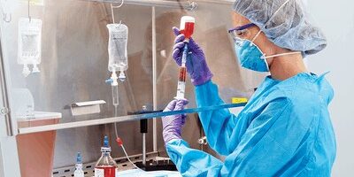 cleanroom worker filling vial wearing usp 800 protective ppe